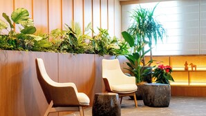 Un'area reception con due poltrone moderne, una parete in legno e una parete verde.