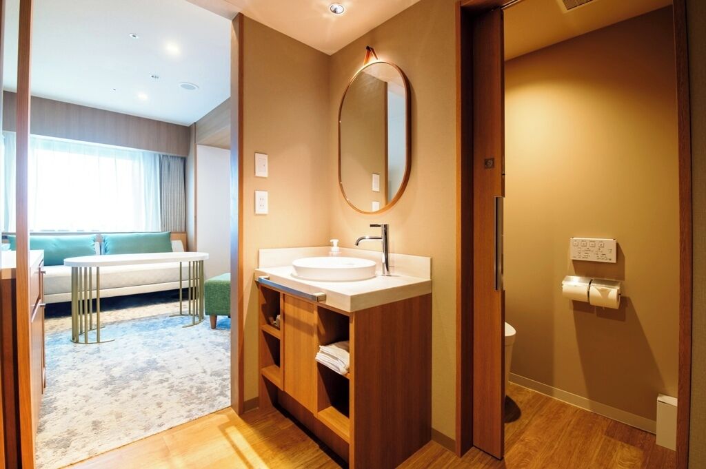 Une salle de bain moderne avec un miroir rond, un lavabo et des toilettes.