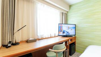 Habitación de hotel con un escritorio de madera, televisión, una silla, cama y pared de textura verde.