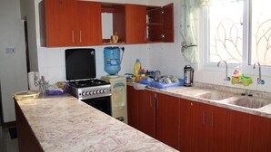 A kitchen with wooden cabinets, a stove, a sink, and a window with a decorative curtain.