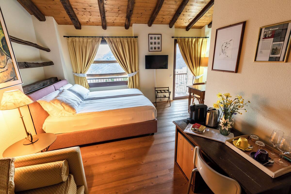 A bedroom with a bed, a desk with a tray of items, a chair, and a window with curtains.