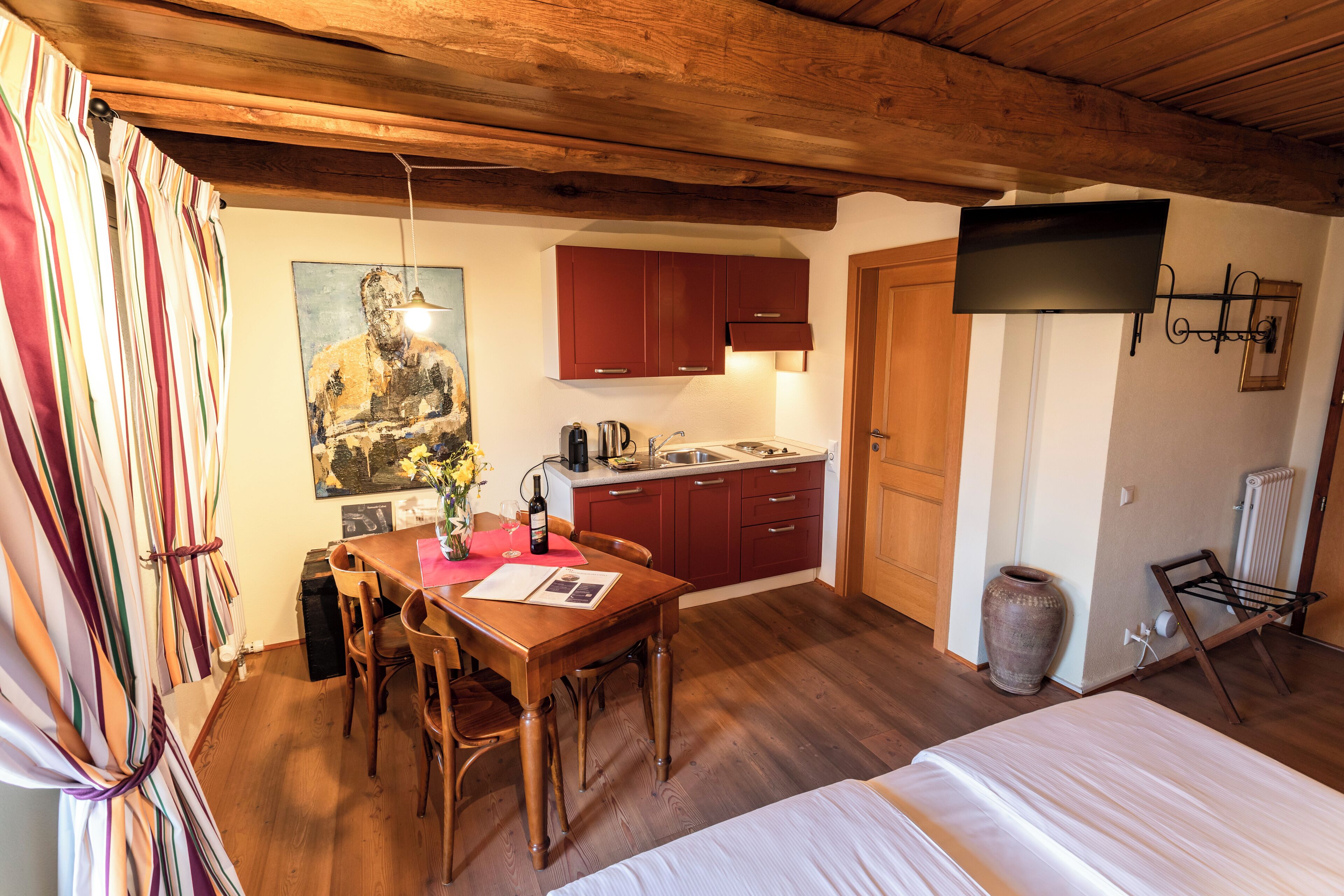 Una cocina acogedora con armarios de madera, una mesa de comedor y un televisor en la pared.