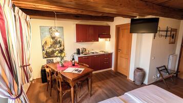 Una cocina acogedora con armarios de madera, una mesa de comedor y un televisor en la pared.