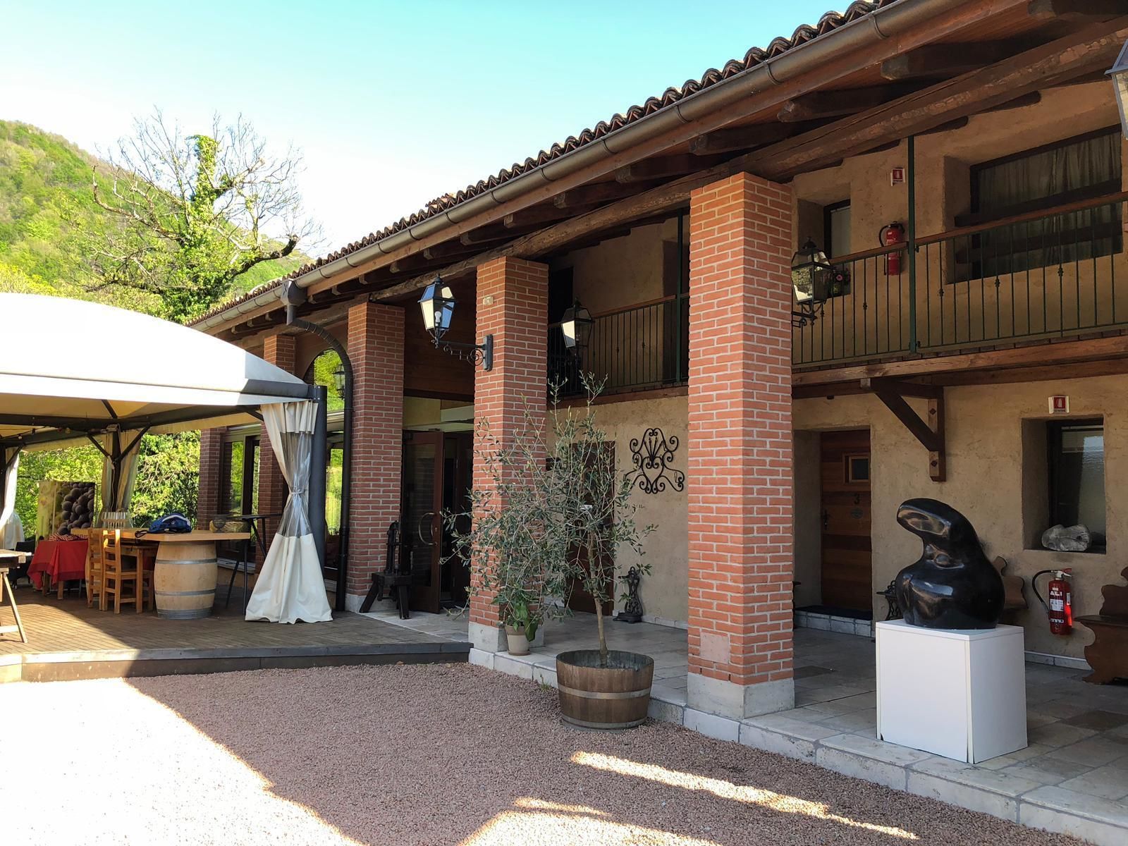 A building with a covered patio area, brick columns, and a balcony.