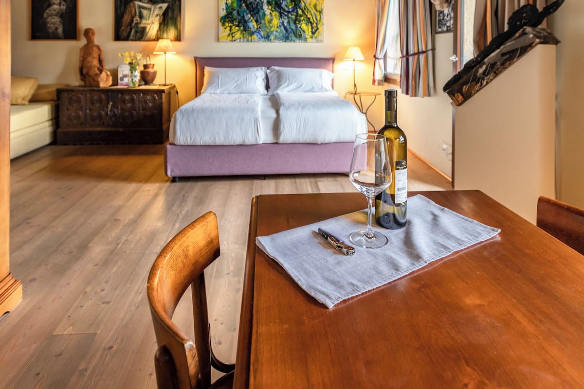 A rustic wooden room with a bed, a dining table, and a chandelier.