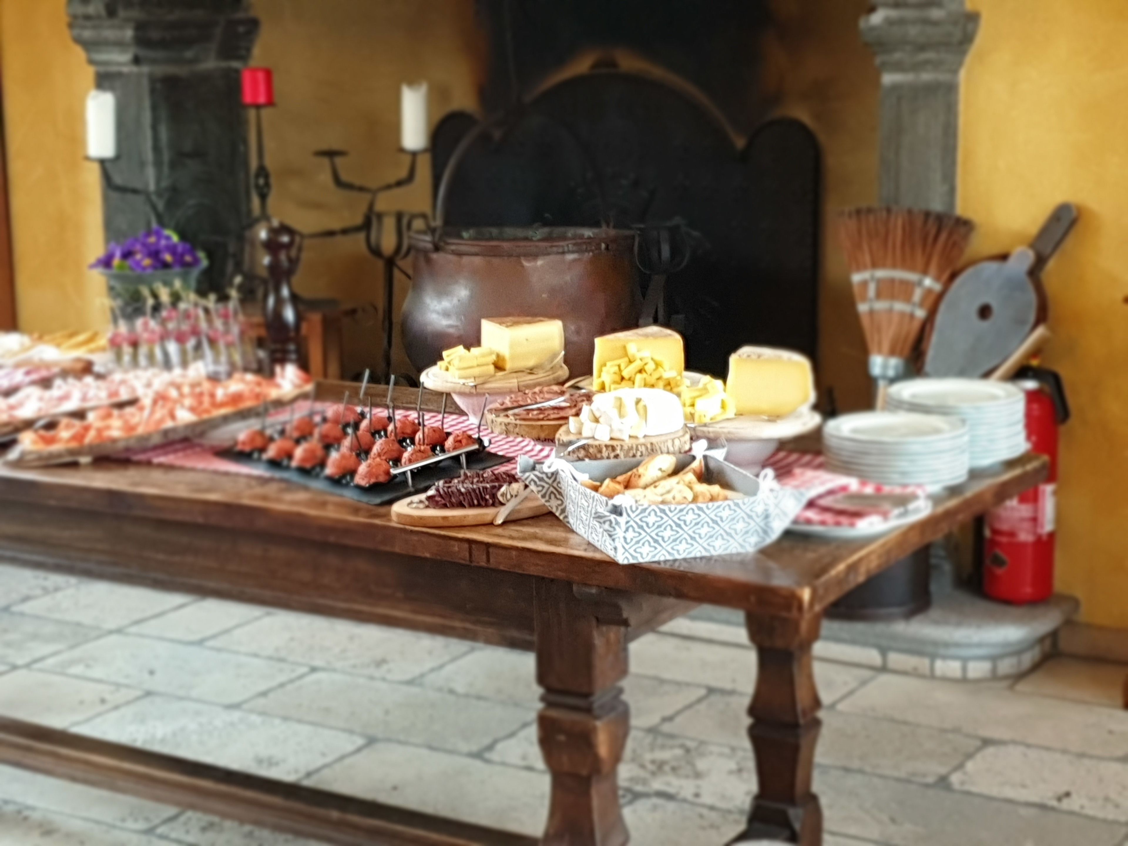 A buffet table with various food items and a large pot in the background.