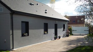 Un bâtiment moderne à l’extérieur gris, doté de nombreuses fenêtres et d’une allée d’accès fermée par un portail.