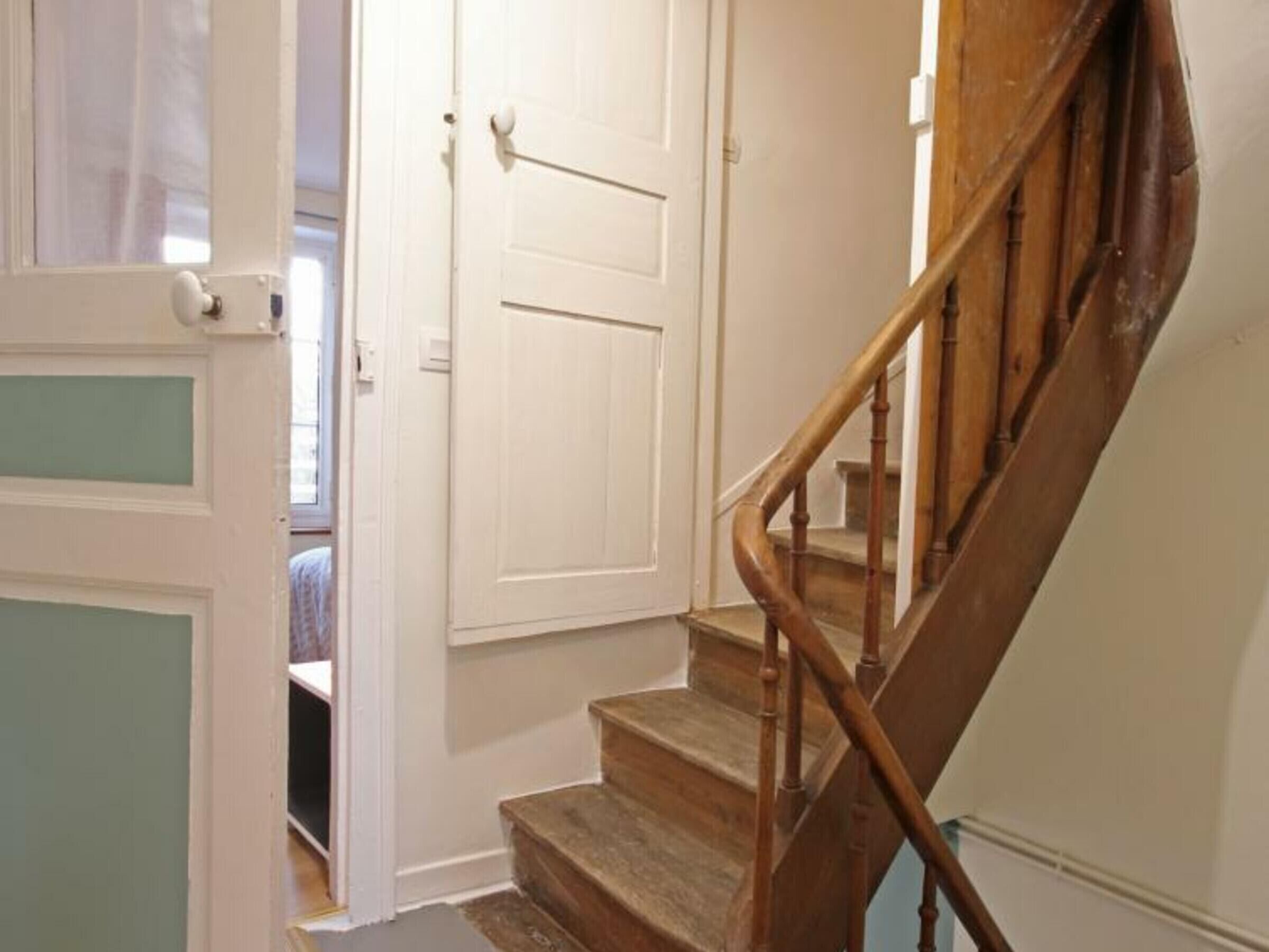 Un escalier avec des rampes en bois menant à une porte blanche.