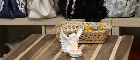 A wooden table with a woven basket containing a Hello Kitty plush toy and a small white angel figurine.