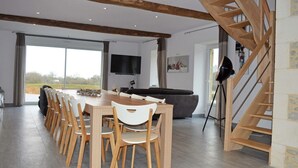 Una cocina moderna con una escalera de madera, un comedor con sillas de madera y un amplio ventanal con vistas al exterior.