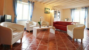 A living room with a tiled floor, white sofas, a red sofa, a coffee table, and a painting on the wall. - Family house in the heart of Perche - 11 guests (Feings)