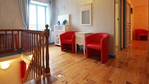 A room with a wooden staircase, a white desk, two red chairs, a white cabinet, and a window with curtains. - Family house in the heart of Perche - 11 guests (Feings)
