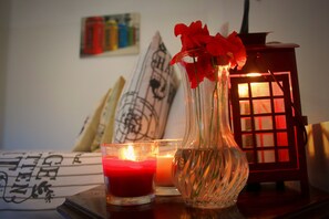 A candle, a glass vase with red flowers, and a lit lantern on a table. - Maltese Maltese (Sliema)