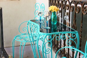 A turquoise metal table with glass top, two chairs, and a vase with yellow flowers. - Maltese Maltese (Sliema)