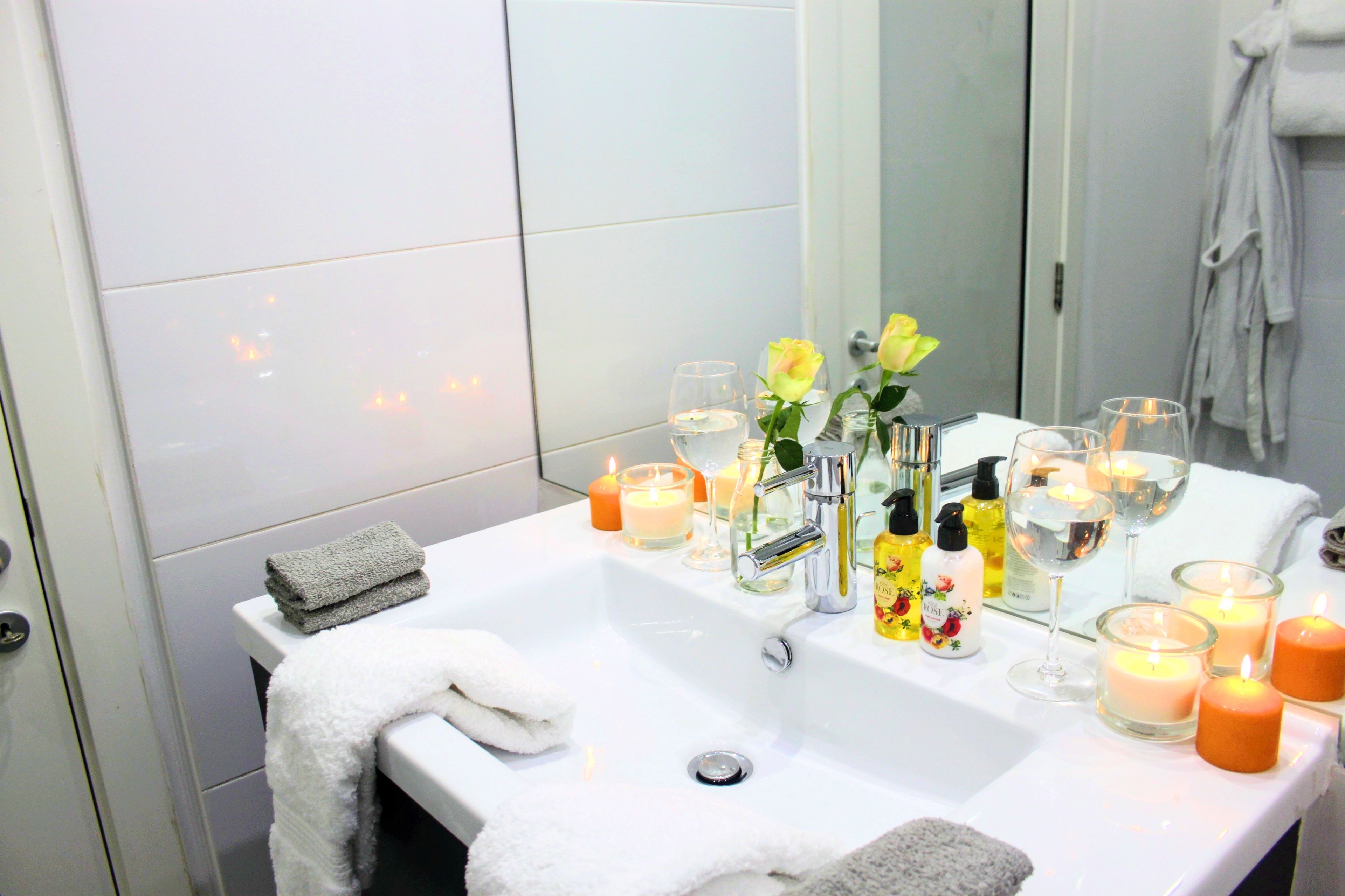 Une salle de bain avec un lavabo blanc, plusieurs bougies et un miroir.