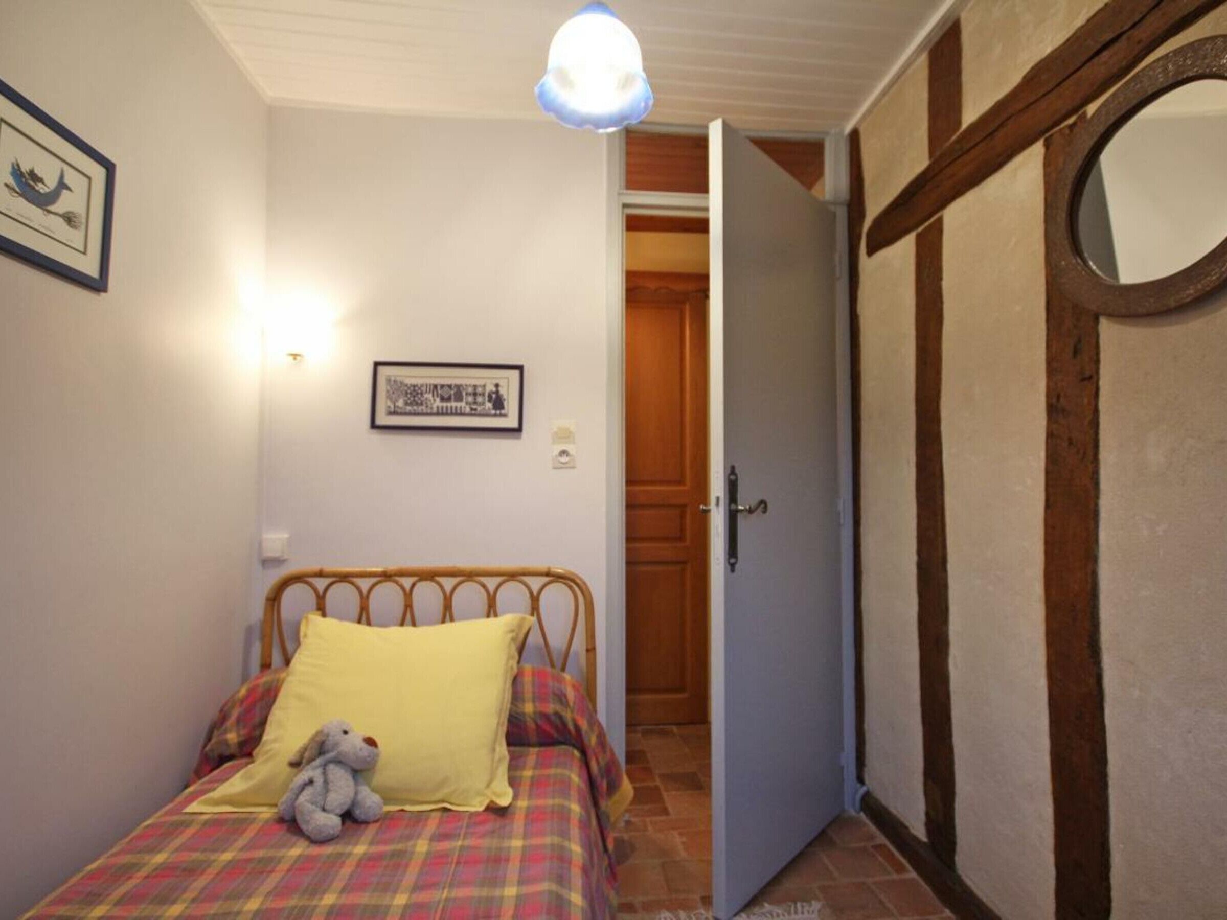 A bedroom with a bed, a wooden door, and a wall-mounted light fixture.