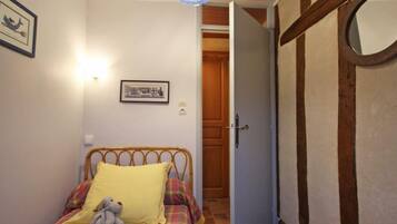 A bedroom with a bed, a wooden door, and a wall-mounted light fixture.
