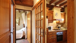 Ein gemütliches Zimmer mit einem Bett, einer Holztür und einer Küche mit Mikrowelle und Herd.
