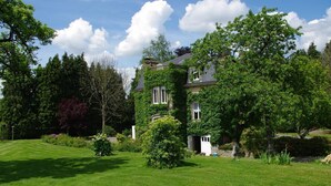 A large house with a well-maintained lawn and surrounding greenery.