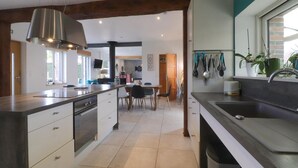 Une cuisine moderne dotée d’un îlot central, d’un coin repas avec des chaises et d’une vue sur le salon.