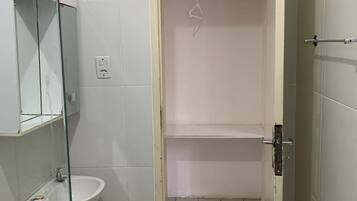 Un baño pequeño con cabina de ducha de vidrio, lavamanos e inodoro.