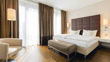 Une chambre d’hôtel avec un grand lit, des tables de chevet, une chaise et un banc.