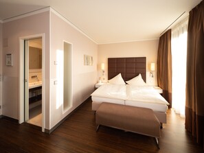 Habitación de hotel con una cama grande, una mesita de noche, un espejo y una puerta que da a un baño.