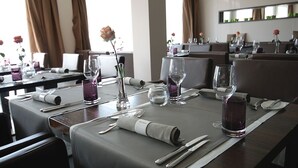 A dining area with tables set for a meal, featuring clear glassware, folded napkins, and a vase with a single rose. - Hotel Eberhards am Wasser (Bietigheim-Bissingen)
