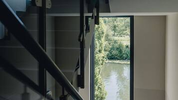 Una escalera moderna con barandas de vidrio que conduce a una puerta con vista al río.