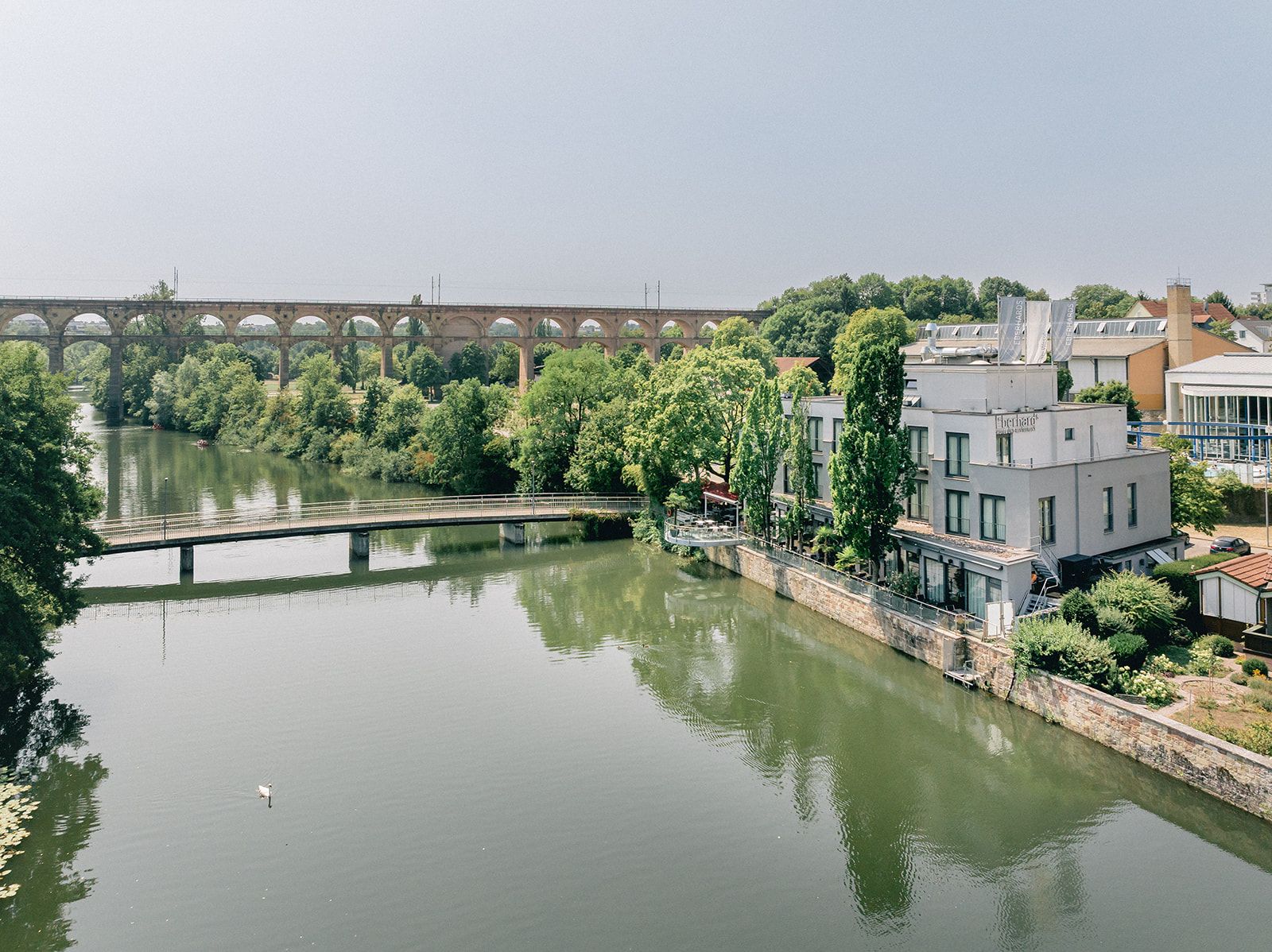 A river with a bridge, trees, and buildings along the banks.