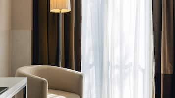 Habitación de hotel con sofá, lámpara y vistas a través de cortinas traslúcidas.