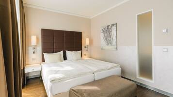 Quarto de hotel com cama grande, mesas de cabeceira, um banco e um quadro na parede.