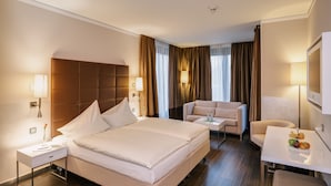 A hotel room with a large bed, a sofa, a small table with fruit, and a TV. - Hotel Eberhards am Wasser (Bietigheim-Bissingen)