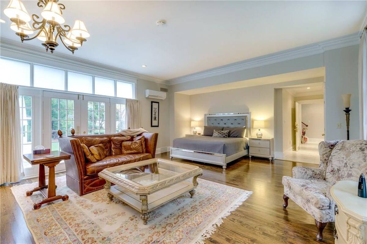 A spacious living room with a leather sofa, a glass coffee table, and a floral armchair.