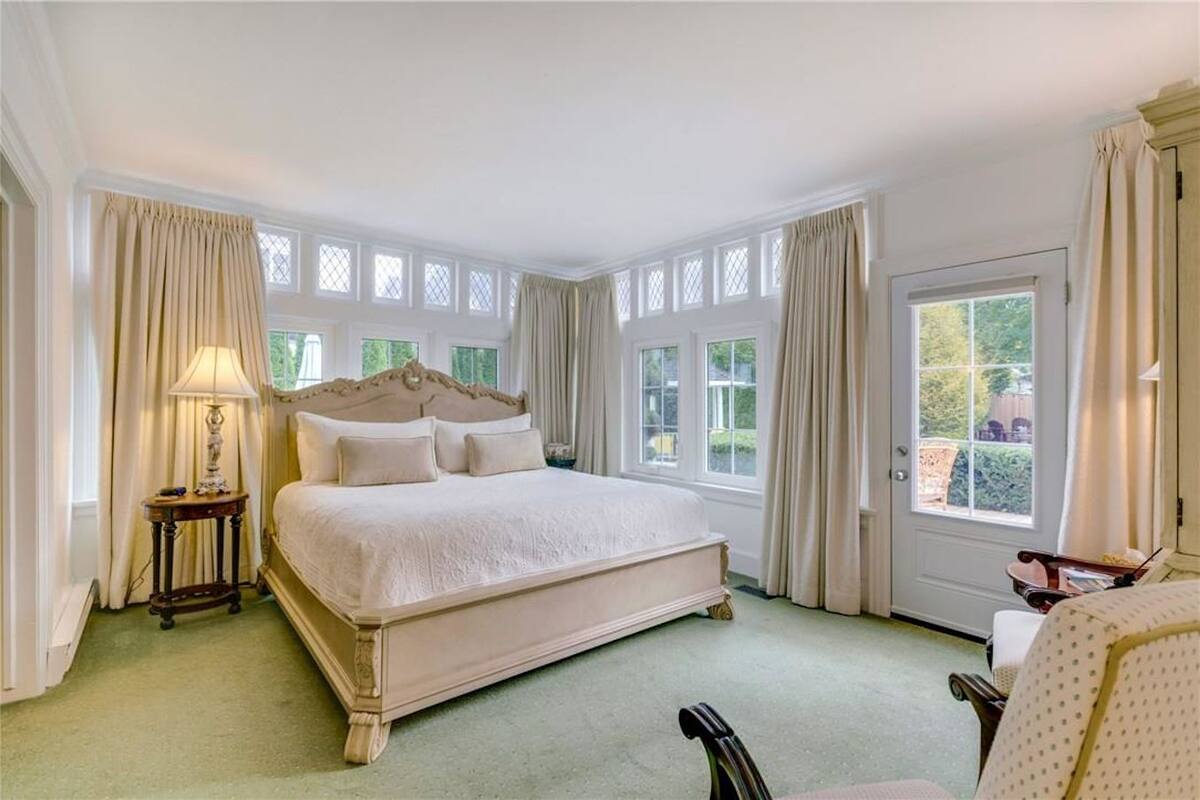 A spacious bedroom with a large bed, multiple windows, and a view of the outdoors.