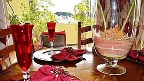 Una mesa de comedor con un mantel rojo, un vaso de bebida roja y un vaso con un postre en capas.