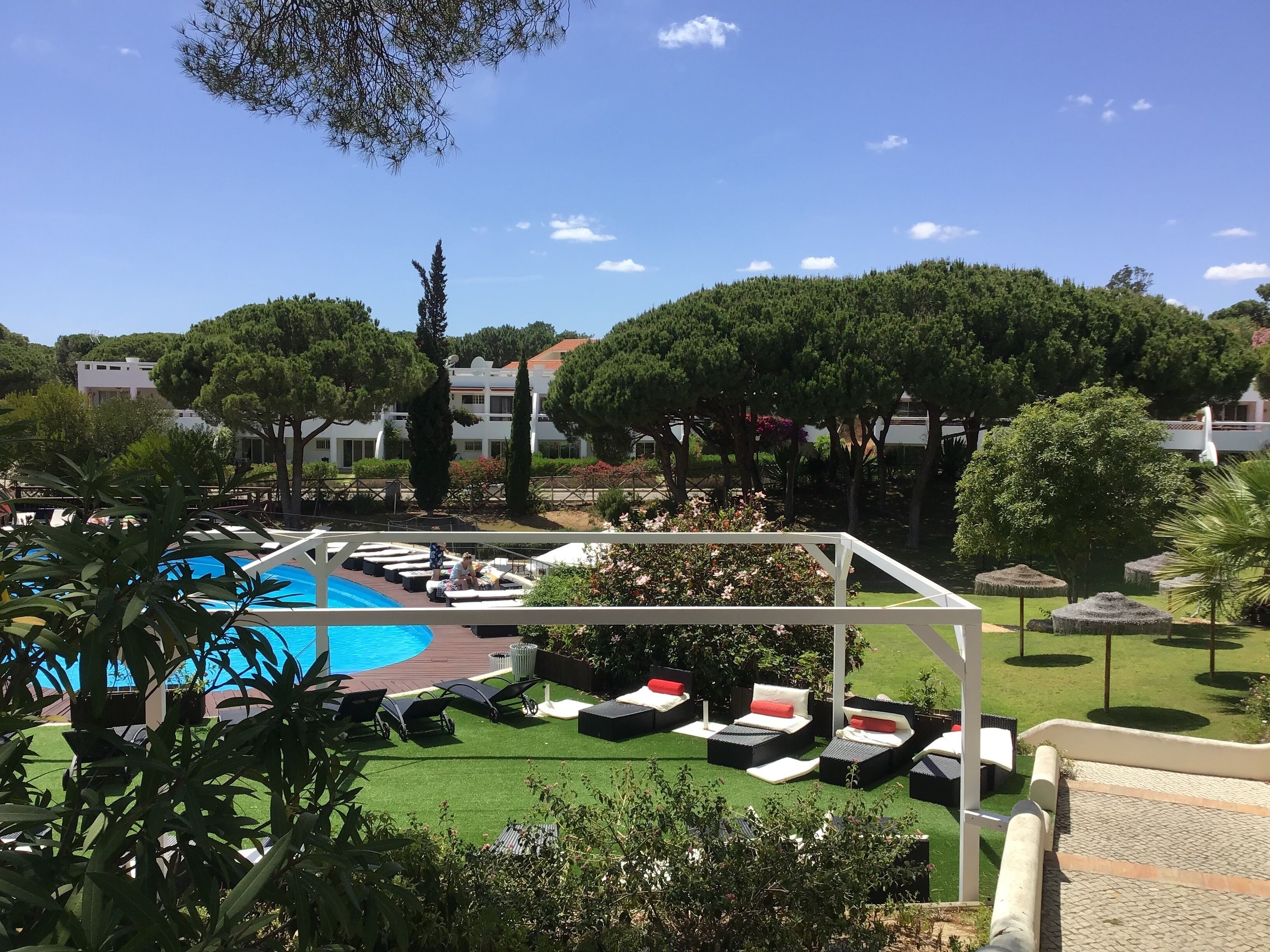 A pool area with lounge chairs and a pergola.