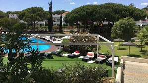 Un área de piscina con sillones de descanso y una pérgola.