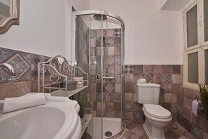 Un baño con ducha de mampara de vidrio, una bañera blanca y un inodoro.