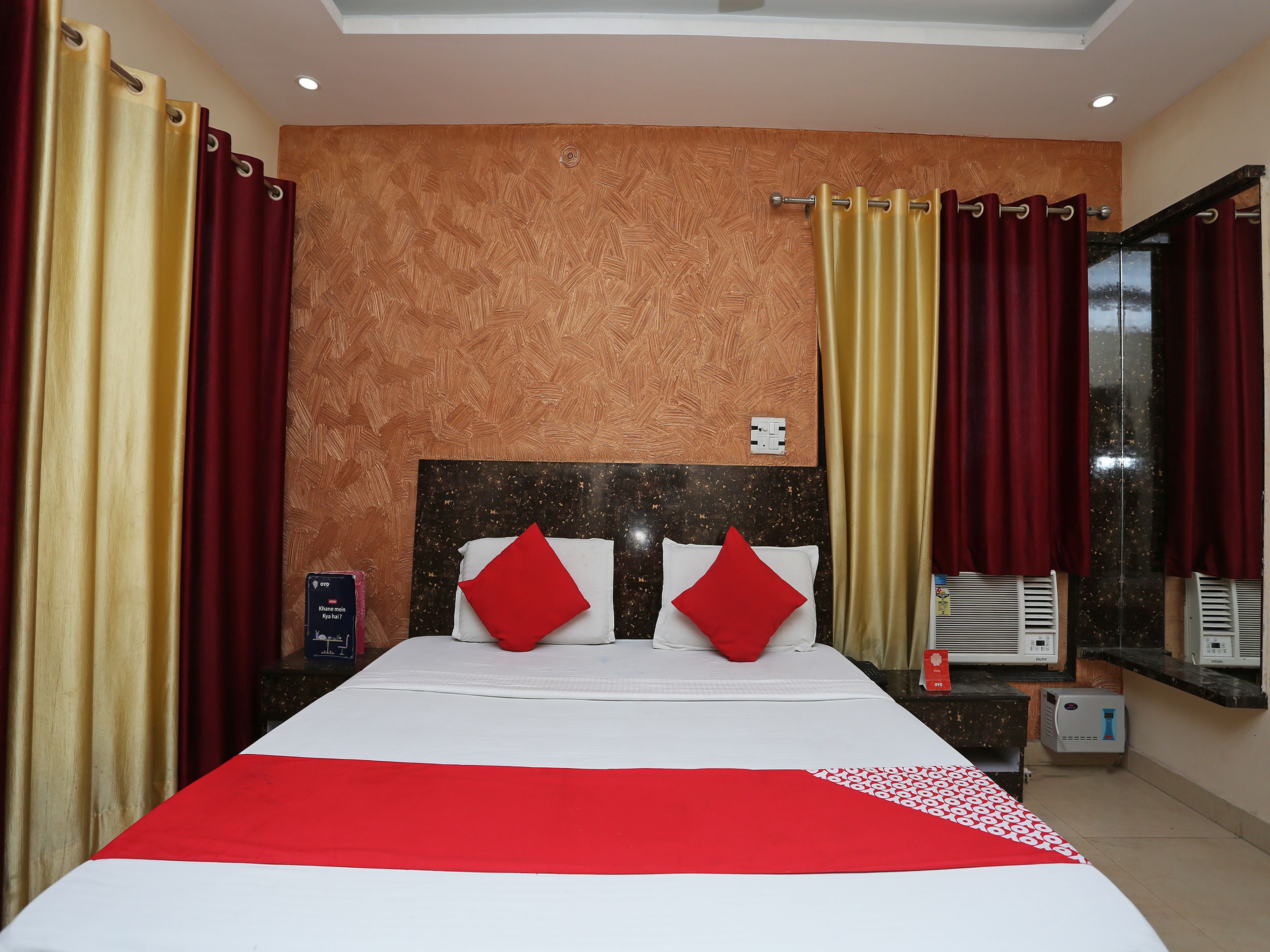 A hotel room with a bed, curtains, a headboard, a nightstand, and a window.