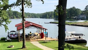 A lakeside deck with outdoor seating, a covered area, and a boat dock.