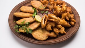 A wooden plate with various fried snacks, garnished with parsley and a lime wedge. - OYO 28187 Hotel Potala (Manali)
