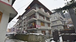 A multi-story hotel with balconies, a stone facade, and a sign indicating it is a hotel. - OYO 28187 Hotel Potala (Manali)
