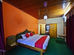 A room with a wooden ceiling, a bed with a red and white bedspread, and a green carpet. - OYO 28187 Hotel Potala (Manali)
