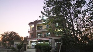 Un hotel de varios pisos con balcones y un cartel que dice 'HOTEL OJUS TOWER'.