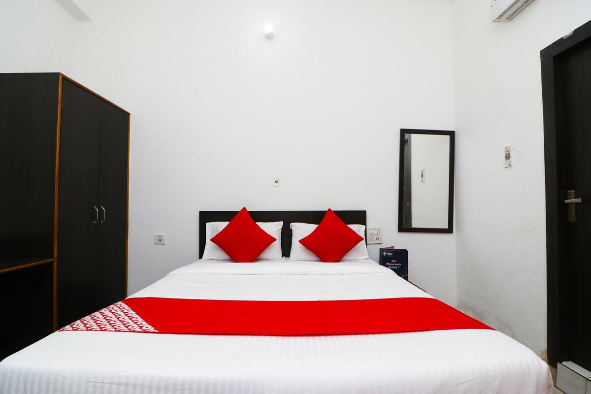 Una habitación de hotel con cama, armario, espejo y puerta.