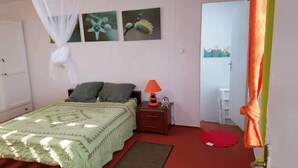 Une chambre à coucher avec un lit, une table de chevet, une lampe et une moustiquaire.