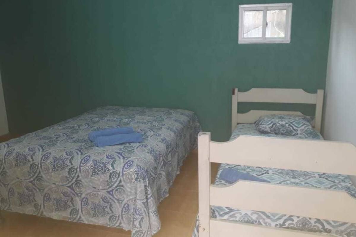 A room with a bed and a bunk bed, both with patterned bedding.