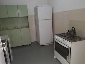 Cuina amb nevera, fogó i armaris verds.