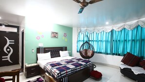 Un dormitorio con cama, mesita de noche, sillón colgante y una ventana con cortinas.